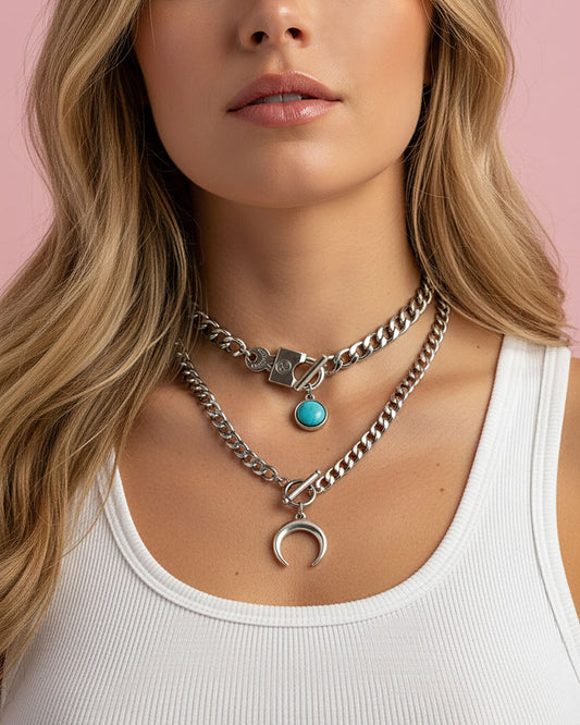 Woman wearing a silver chain necklace with a crescent moon pendant and a silver chain necklace with turquoise pendant