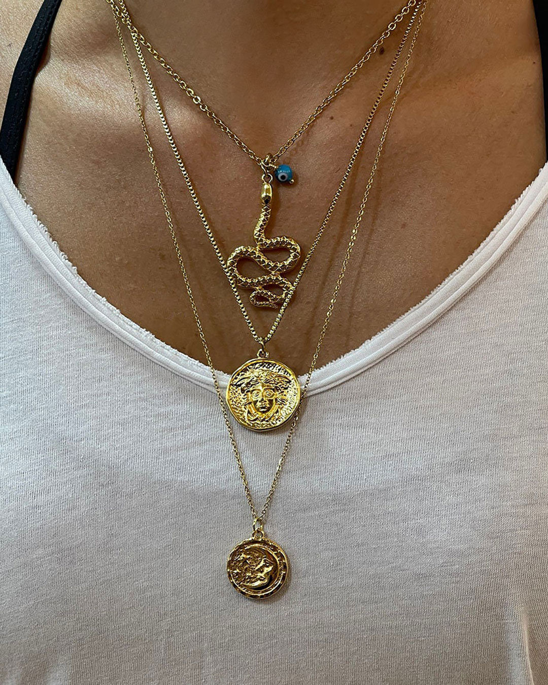 Model wearing a multilayer necklace in gold with moon and snake charms
