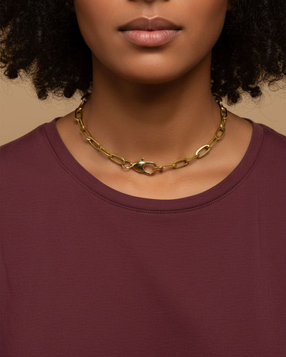 Model wearing a gold chain necklace with a heart shaped closure