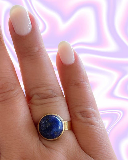 Hand wearing a gold waterproof adjustable band ring with a lapis lazuli stone