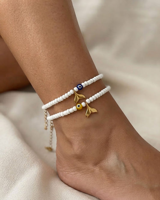 Beaded anklets adorned with gold tail and colorful evil eye bead on a foot