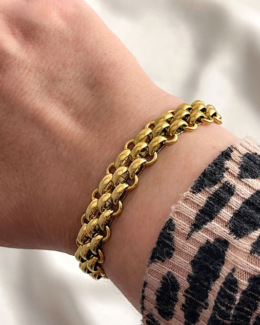 A wide gold woven style chain bracelet made from stainless steel.