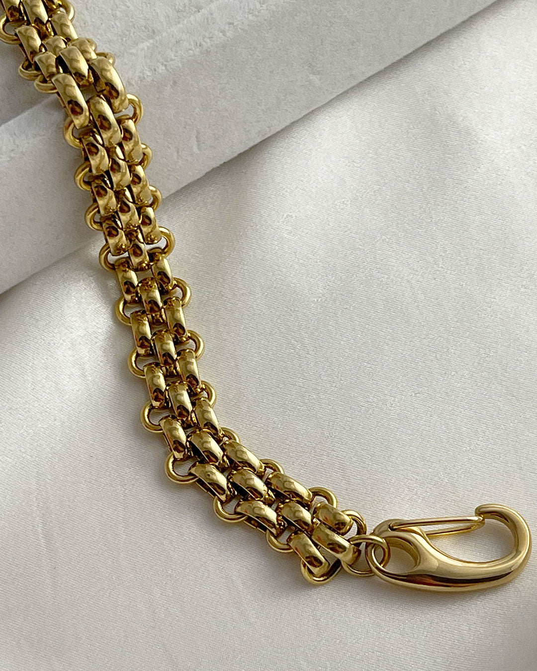 A wide gold woven style chain bracelet made from stainless steel with a large lobster clasp.