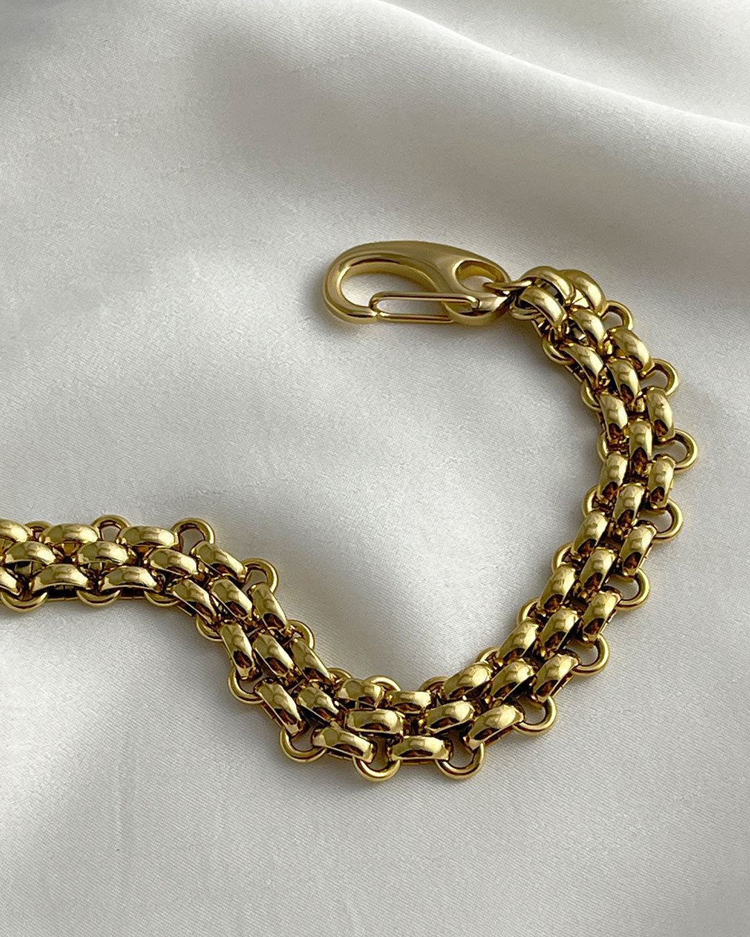 A wide gold woven style chain bracelet made from stainless steel with a large lobster clasp.