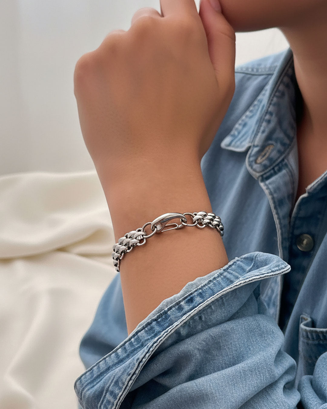 Silver chain bracelet on a wrist with a denim jacket