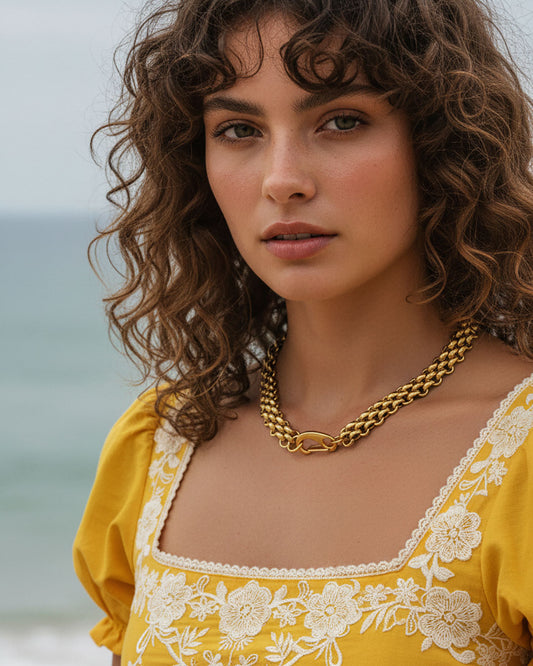 Model wearing a gold chainmail necklace with a large lobster clasp