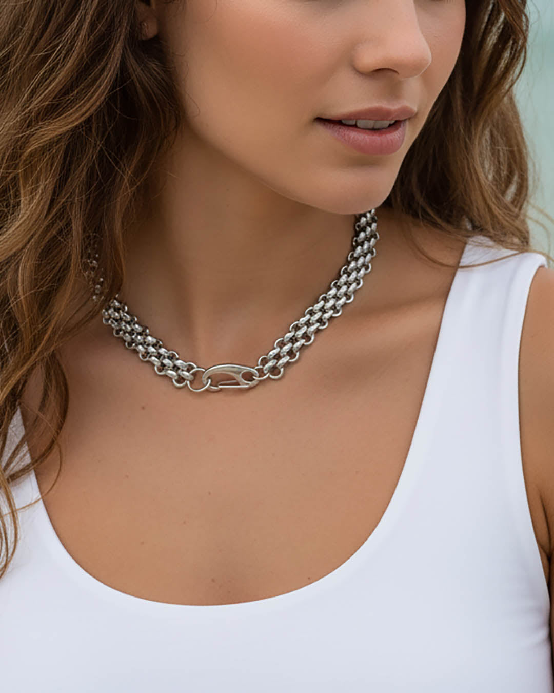 Model wearing a silver chainmail necklace with a large lobster clasp