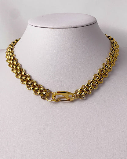 A gold woven wide chain necklace with a large lobster clasp