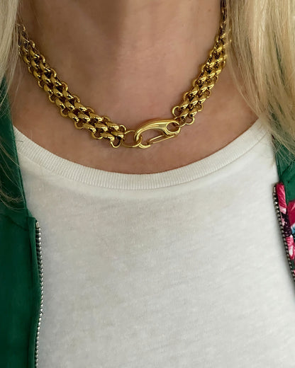 A woman wearing a gold woven wide chain necklace with a large lobster clasp