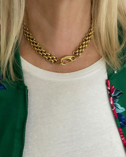 A woman wearing a gold woven wide chain necklace with a large lobster clasp