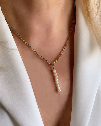 Model wearing a pearl drop necklace with a dainty chain