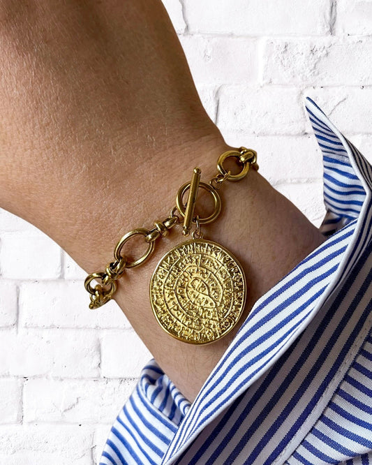 Model wearing a Phaistos Disc Charm Bracelet in gold with a toggle closure