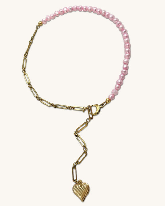 A pink freshwater pearl statement lariat necklace with a gold paperclip chain and a hanging heart pendant