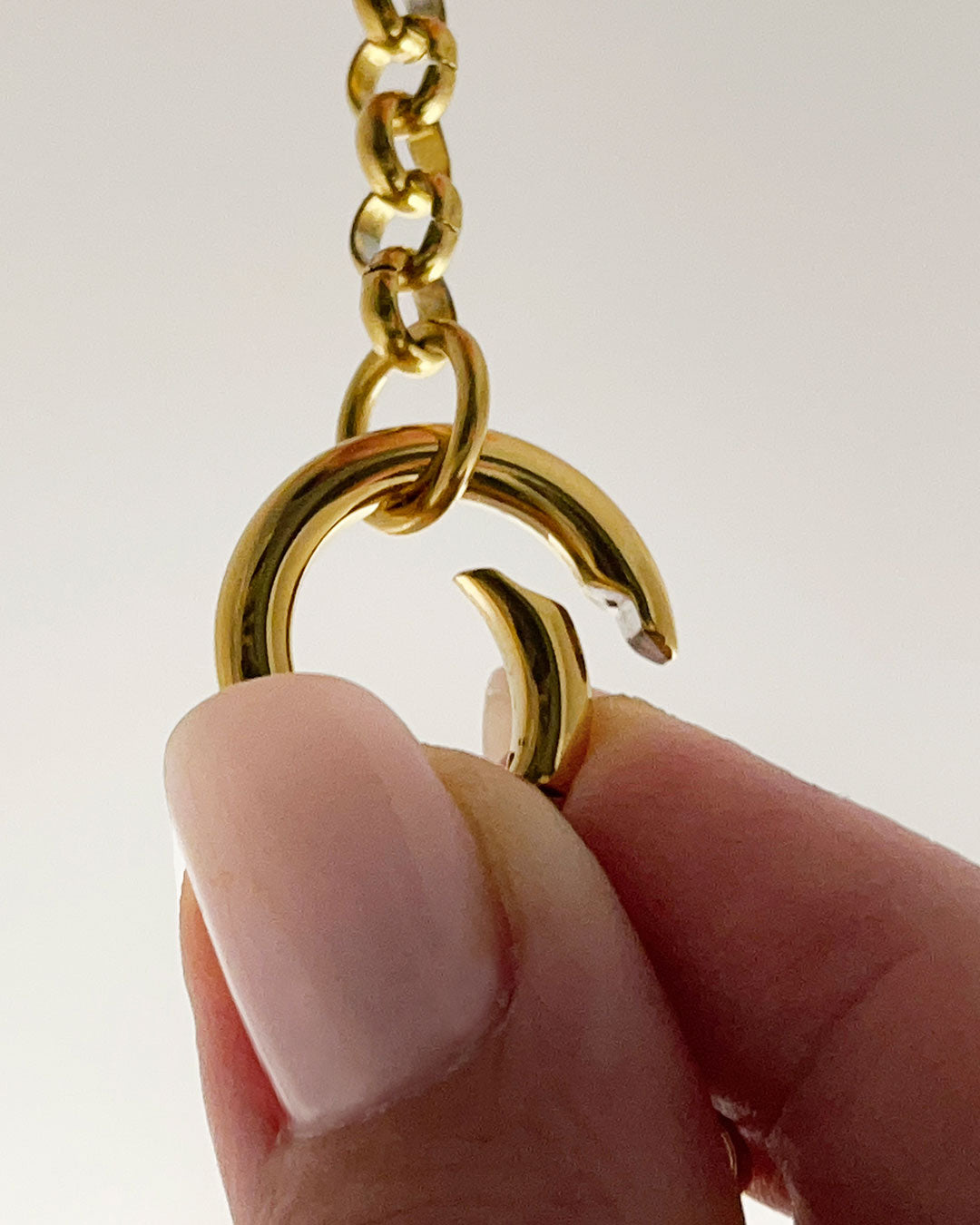 A close up of gold rolo chain necklace with a simple circular closure