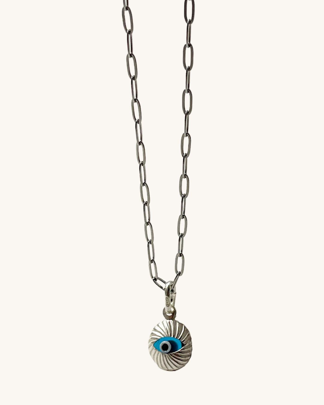 A silver paperclip chain necklace with a blue and silver evil eye pendant. The pendant is round and has a textured surface.
