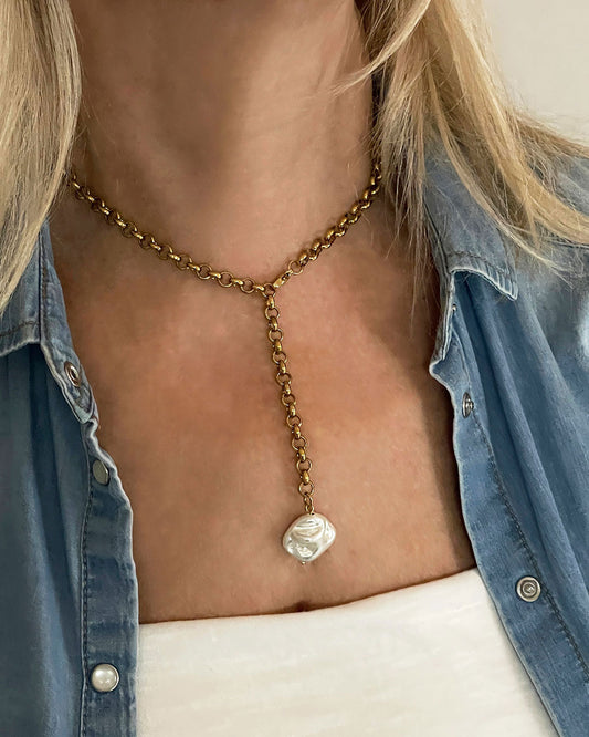 Gold chain necklace with a MOP shell pearl pendant worn by a model in a denim shirt.