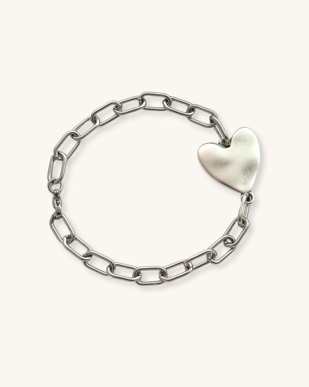 Silver chain bracelet with a heart-shaped charm on a white background