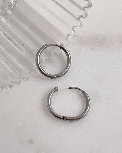 Pair of silver hoop earrings 14mm on a light gray surface.