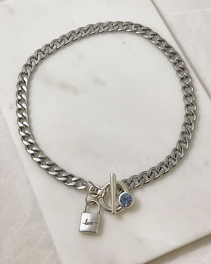 A silver chain necklace with a padlock charm that says 'love' and an aquamarine Swarovski crystal toggle clasp.