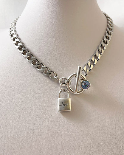 A silver chain necklace with a padlock charm that says 'love' and an aquamarine Swarovski crystal toggle clasp.