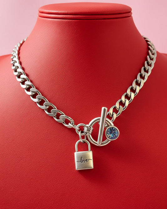 A silver chain necklace with a padlock charm that says 'love' and an aquamarine Swarovski crystal toggle clasp.