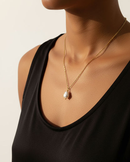 Model wearing a single pearl necklace in gold
