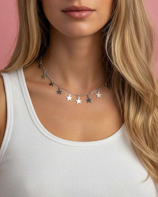 Silver necklace with star pendants worn by a woman against a pink background