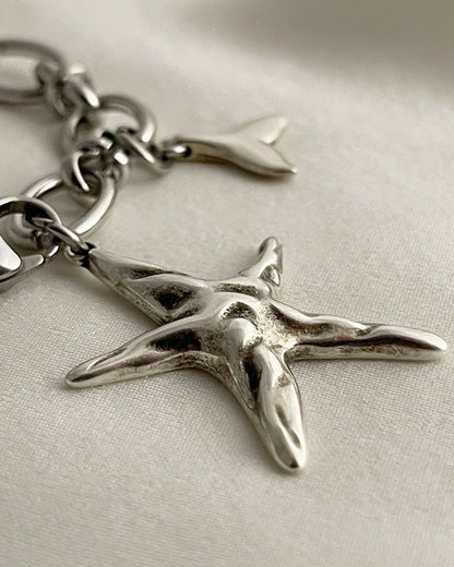 Silver starfish charm on a chain against a light background