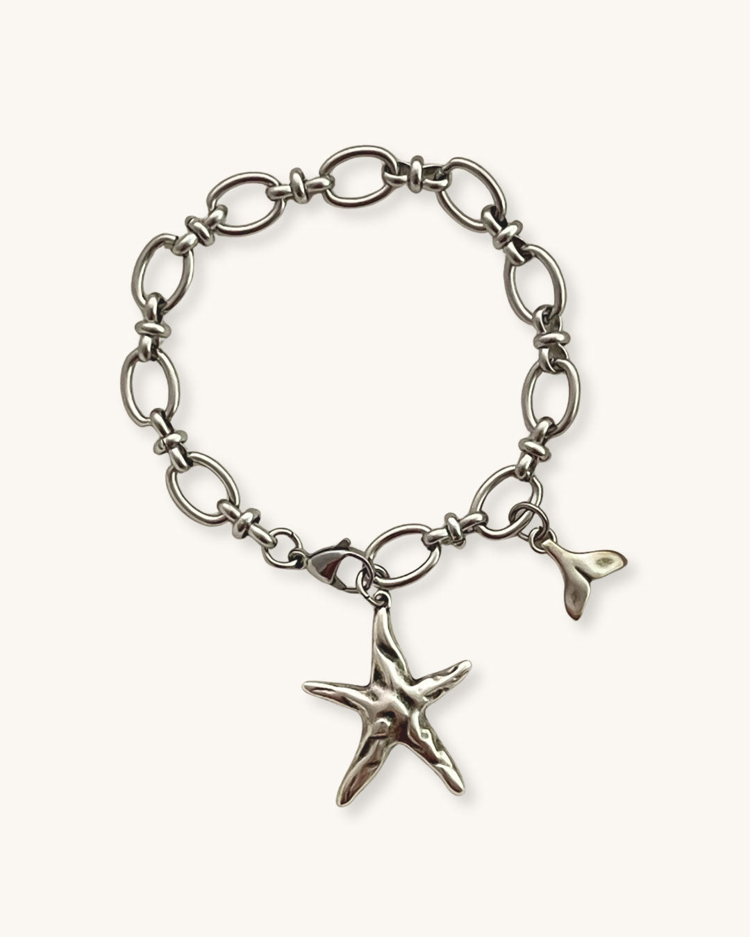 Silver bracelet with a starfish charm on a beige fabric background