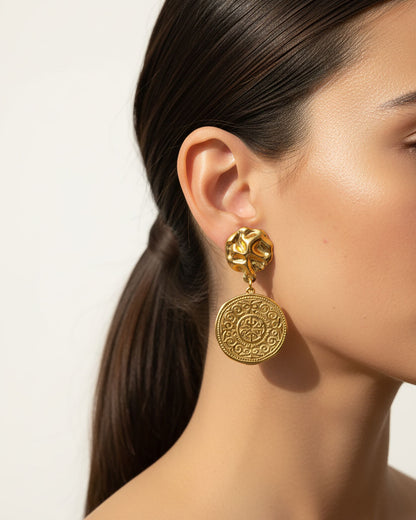 Model wearing a gold drop earrings with an ethnic design coin charm