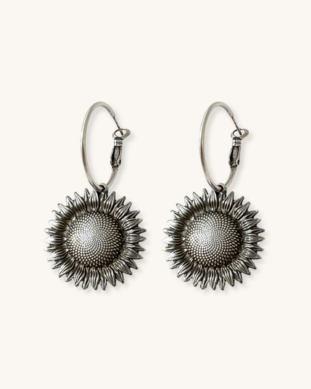 Pair of silver sunflower earrings on a white background