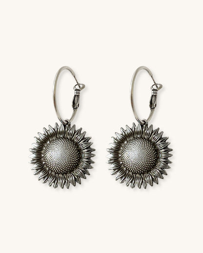 Pair of silver sunflower earrings on a white background