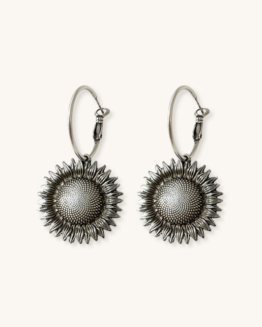 Pair of silver sunflower earrings on a white background