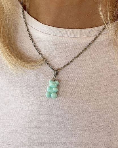 Model wearing an acrylic turquoise teddy bear pendant on a dainty stainless steel silver chain