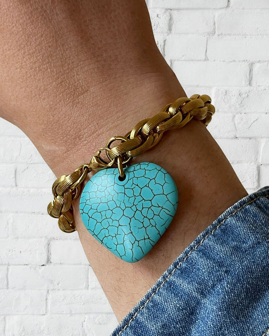 A gold chunky chain bracelet with a large turquoise gemstone heart charm