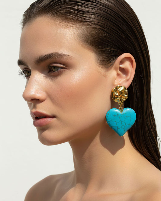Model wearing a pair of turquoise howlite heart-shaped earrings