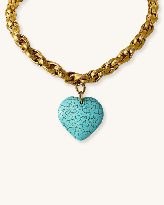 Gold chain necklace with a turquoise heart-shaped pendant on a white background