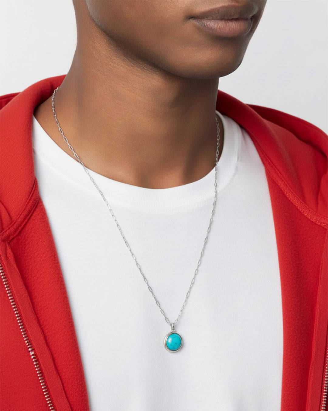 Man wearing a silver paperclip chain necklace with a turquoise pendant