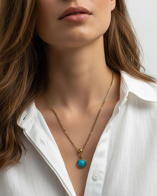 Woman wearing a turquoise pendant necklace in gold