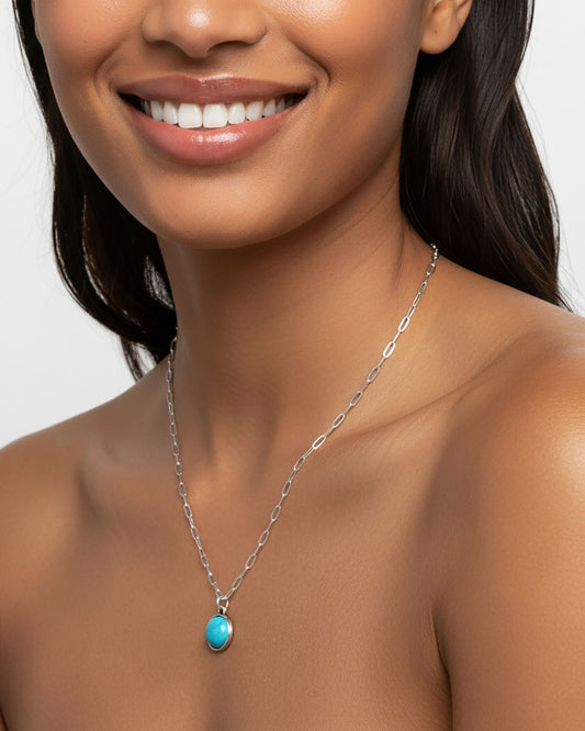 Woman wearing a silver paperclip chain necklace with a turquoise pendant