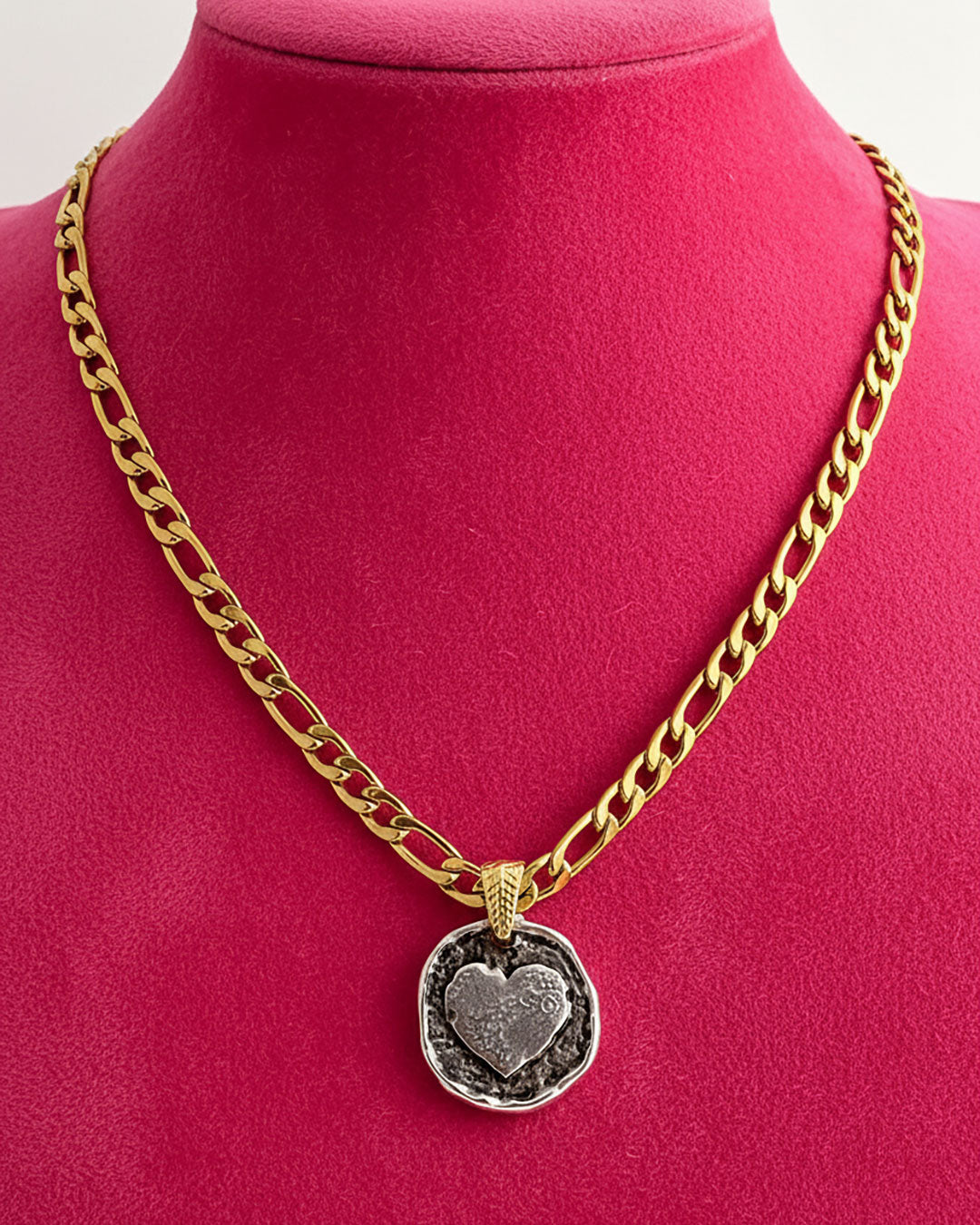 A gold figaro chain necklace with a silver round heart pendant