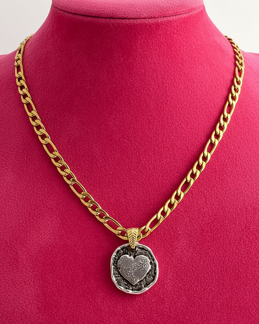 A gold figaro chain necklace with a silver round heart pendant