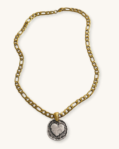 A gold figaro chain necklace with a silver round heart pendant 