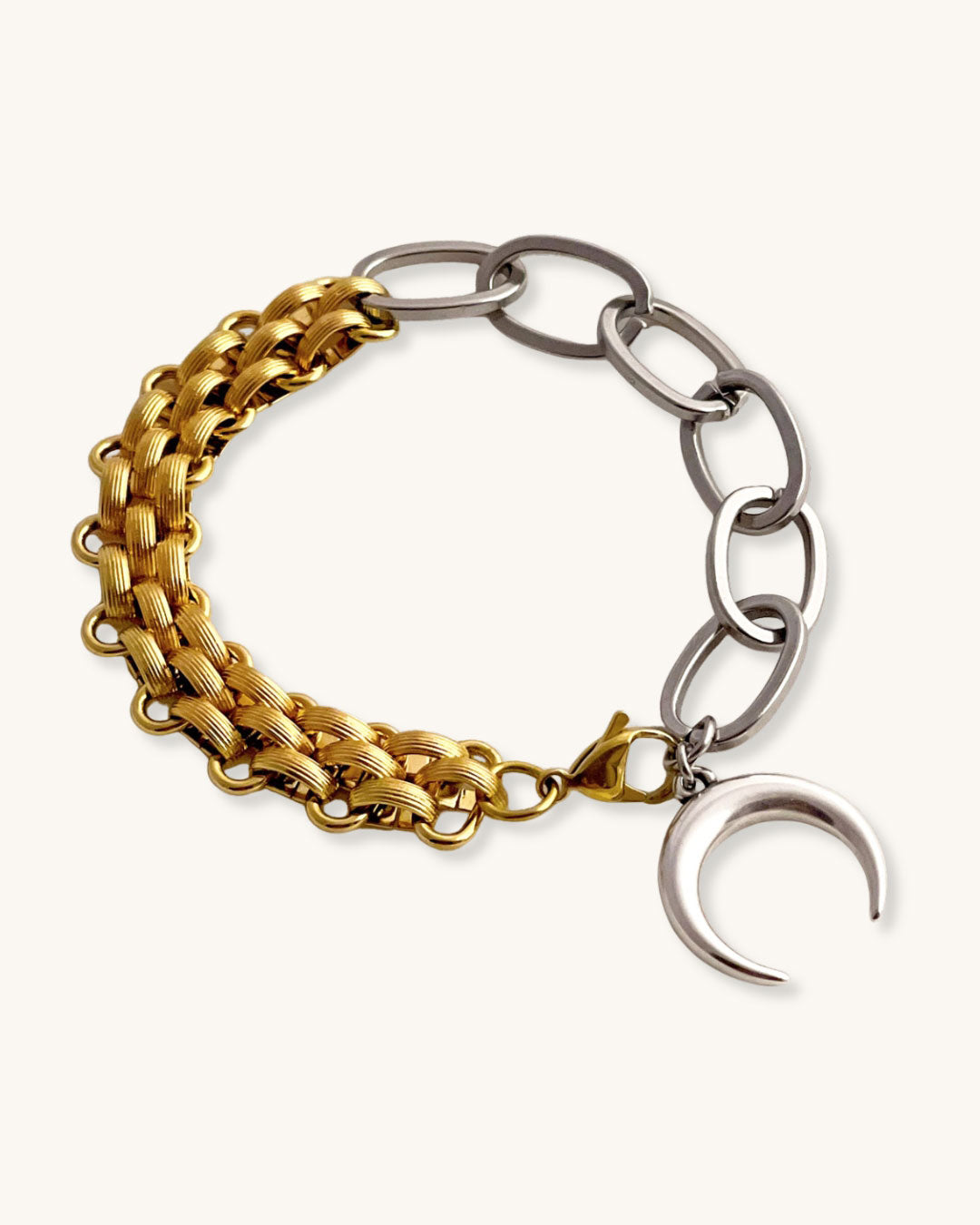 Bracelet with gold and silver chain links and a moon charm on a light background