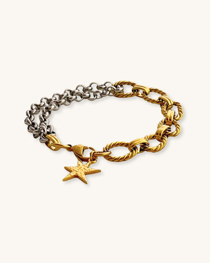 Two chain bracelets, one gold and one silver with a gold charm charm on a light background
