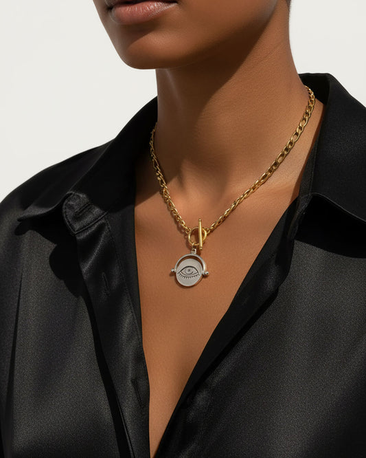 Gold necklace with a silver eye pendant worn by a model against a neutral background