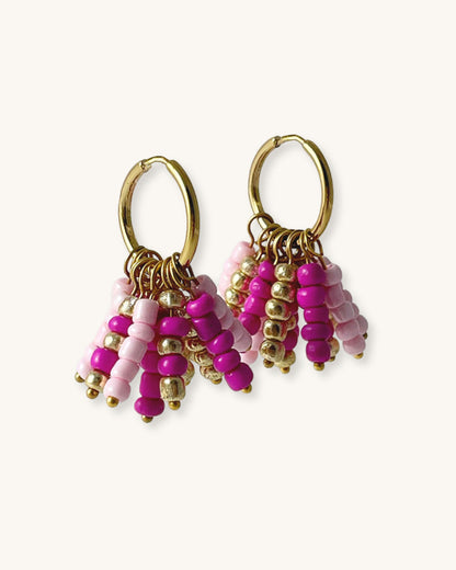 Pair of beaded hoop earrings with pink and gold details on a white background