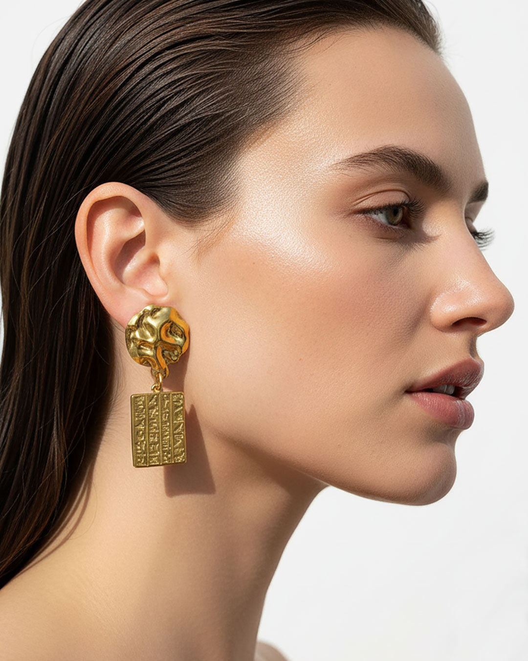 Model wearing gold dangle earrings Egyptian style wth hieroglyphic tags