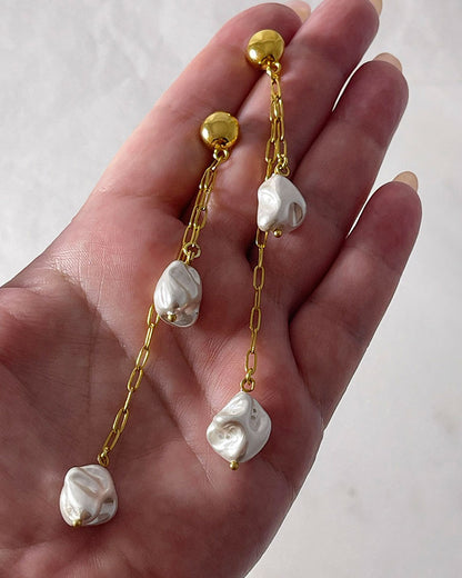 The Long Drop Pearl Shell Earrings, a pair of stud earrings featuring two paperclip chains with shell pearl pendants.