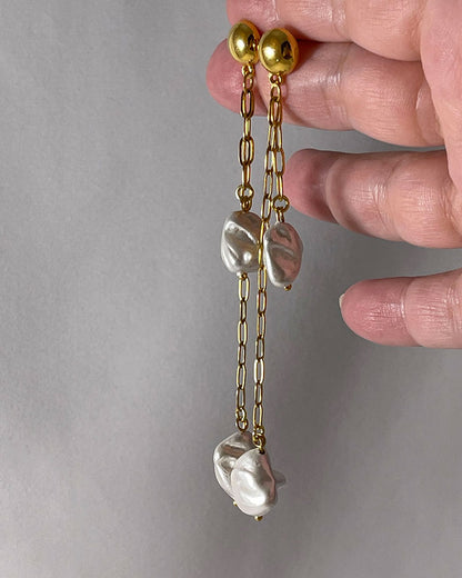 The Long Drop Pearl Shell Earrings, a pair of stud earrings featuring two paperclip chains with shell pearl pendants.
